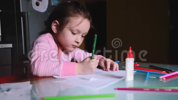 可爱的小白种人女孩穿着粉红色毛衣用铅笔在一张纸上画形状和别人说话视频的预览图