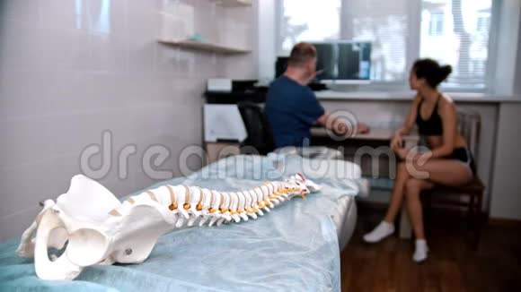 脊椎治疗医生在手术前检查年轻妇女人体脊柱模型视频的预览图