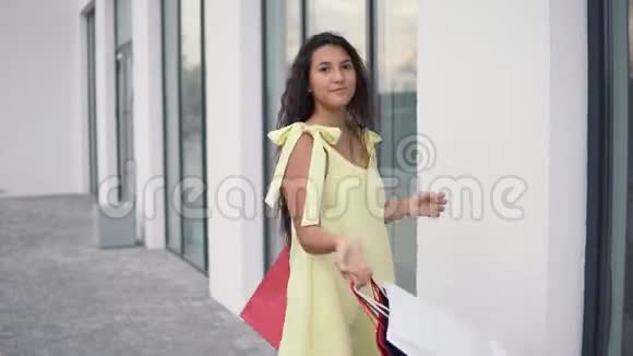 一个漂亮的女孩在购物后带着一个好心情旋转着包裹4K视频的预览图