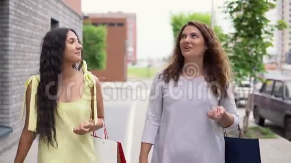 两个有魅力的女朋友正走在街上讨论购物后的问题4K视频的预览图