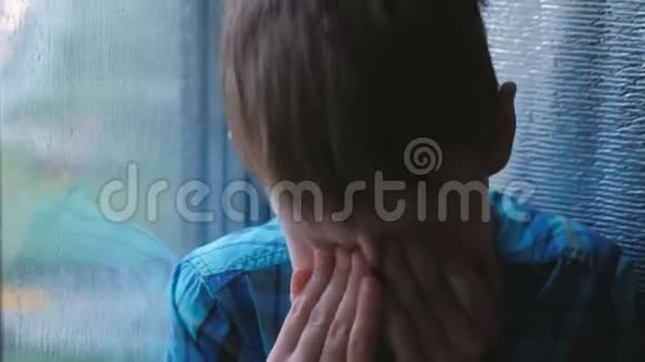 哭泣的男孩在雨中看着窗外视频的预览图