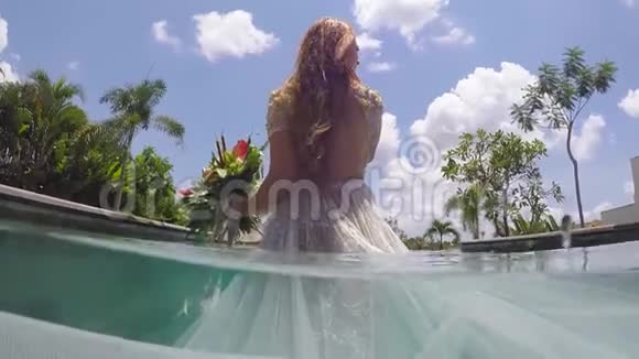新娘穿着婚纱在一个热带别墅的游泳池里水下视频的预览图