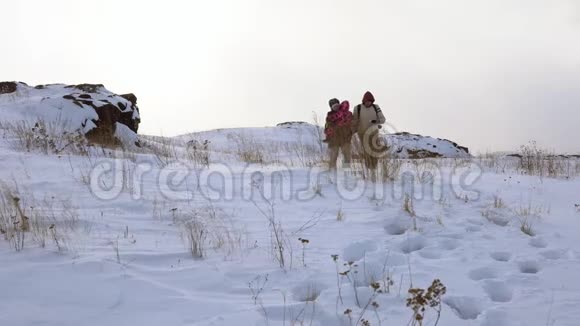 一家人沿着白雪覆盖的小山散步暴风雪开始了视频的预览图
