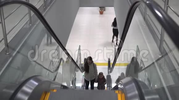 妈妈和女儿站在自动扶梯上爬起来的时候手牵手视频的预览图