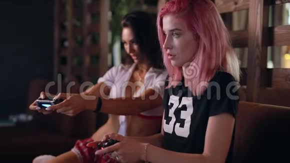 两个性感女孩在玩电视游戏拿着操纵杆视频的预览图