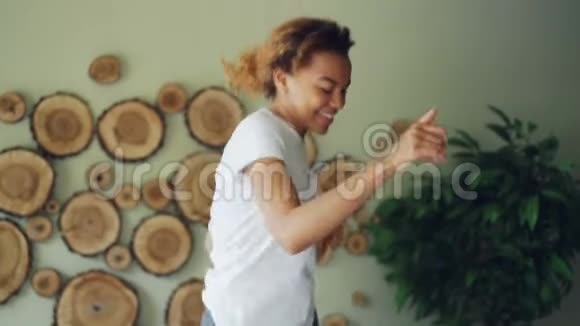 活跃的非洲裔美国妇女听音乐在床上跳舞在家中卧室里唱歌当宠物视频的预览图