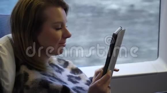 一位坐火车的年轻女士在用平板电脑视频的预览图