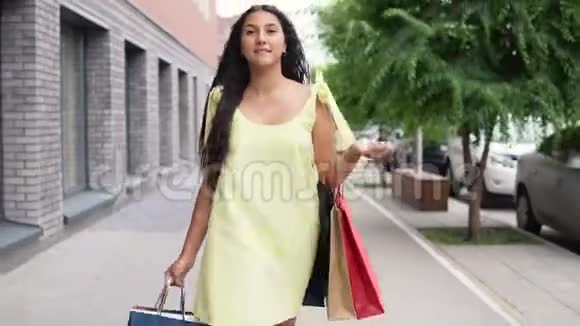 一个穿着黄色长裙的年轻女孩在购物后心情愉快地环游城市4K视频的预览图