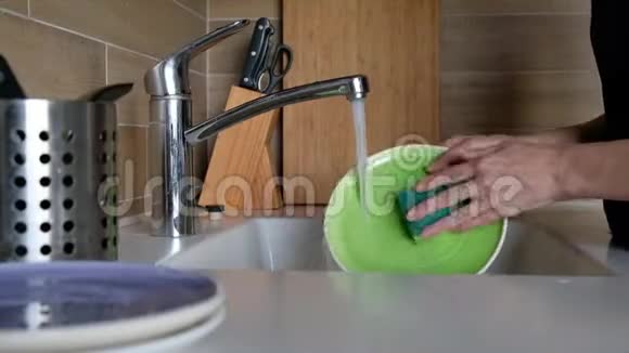 女人的手在厨房水槽里冲洗盘子在家里做家务洗碗常规静态摄像头快关门视频的预览图