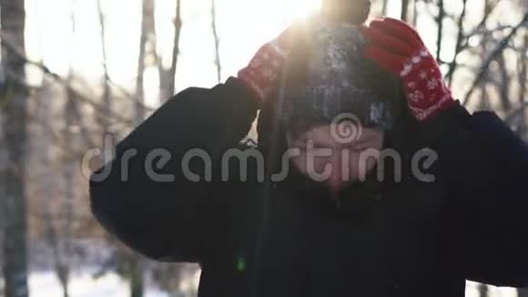 一个穿夹克衫的年轻人把他的引擎盖从他的冬帽上摇下雪的肖像特写镜头视频的预览图