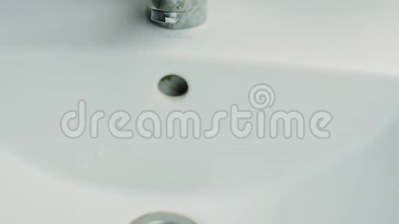 一个男人在浴室的水龙头下洗手视频的预览图