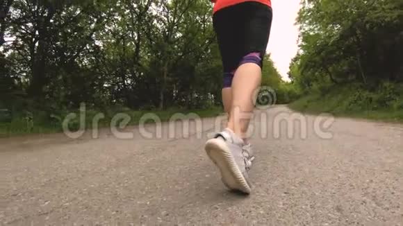 在森林里慢跑之前苗条女孩的特写腿围绕物体的低角度运动视频的预览图