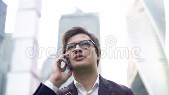 自信的年轻商人在莫斯科市用他的电话说话视频的预览图