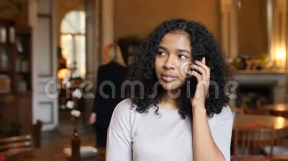 年轻的非裔美国黑人妇女在咖啡馆里用手机聊天视频的预览图