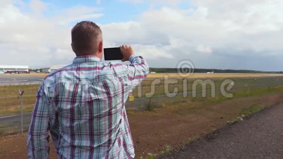 男子在机场跑道附近的智能手机拍照视频的预览图