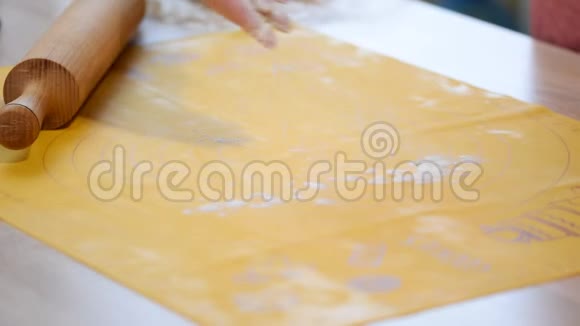 女人的手在家里的厨房里用擀面杖在面粉里擀面团视频的预览图