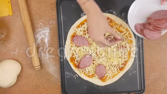 在奶酪覆盖的披萨上一个面目全非的男人或女人的厨师把切片的香肠拼出来做开胃菜视频的预览图