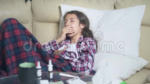 十几岁的女孩感冒了吹着鼻子躺在被子下面的沙发上视频的预览图