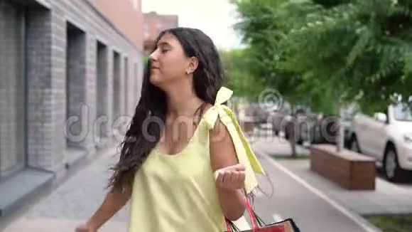 穿着黄色连衣裙的黑发快乐的年轻女孩购物后心情愉快慢动作肖像视频的预览图