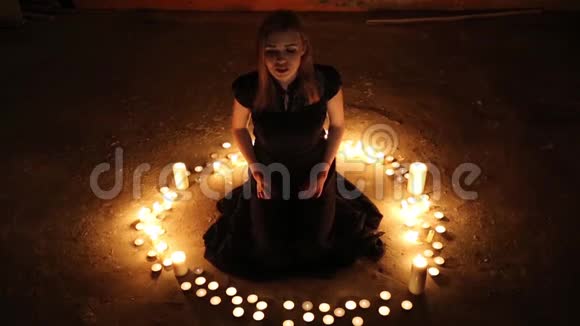 女孩坐在地板上燃烧的蜡烛中视频的预览图