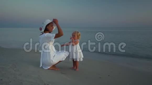 日落时分年轻漂亮的女人和她的小女儿在海滨散步妈妈和她可爱的小女儿试着视频的预览图