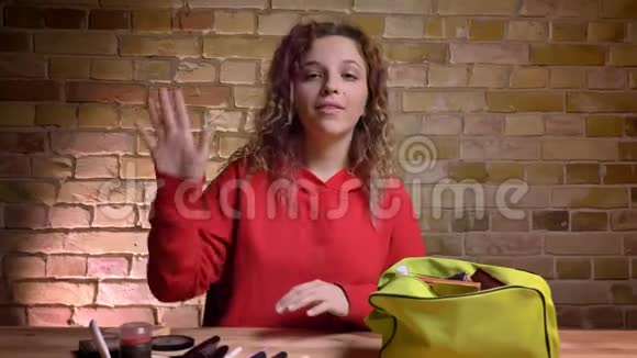 年轻美女博主的特写肖像在镜头前录制关于在布里克肯墙上使用化妆品的视频视频的预览图