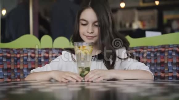 漂亮的女孩欣赏柠檬水在咖啡馆里服务4K视频的预览图