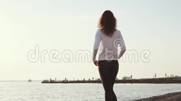 一个女人举起双手在海面上呼吸新鲜的海风视频的预览图