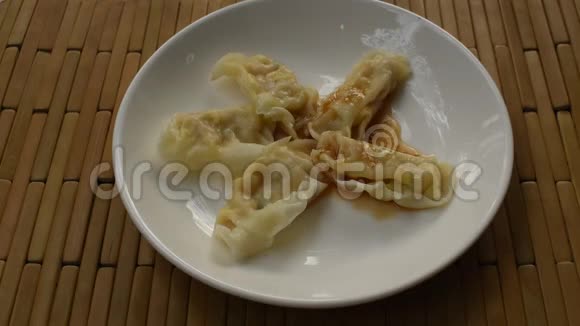 日式蒸饺或豆沙馅猪肉馅在盘子上调味酱油用木筷子夹食视频的预览图