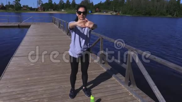 女人在湖边公园健身前热身视频的预览图