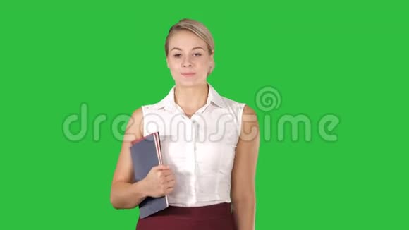 漂亮的年轻女人带着笔记本走在绿色屏幕上Chroma键视频的预览图