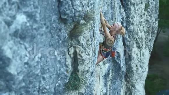 年轻女子攀岩者试图爬上悬崖寻找伸手和抓住视频的预览图