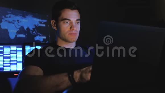 一个英俊的男性黑客程序员晚上在一个充满监控屏幕的数据中心工作视频的预览图
