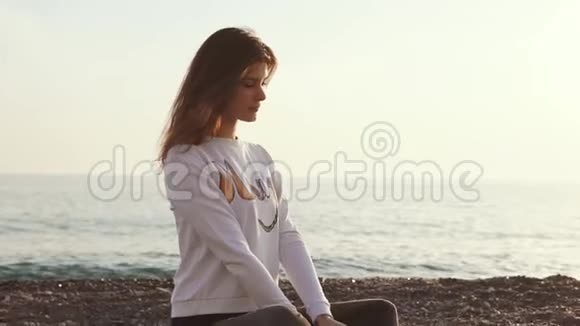 可爱的女人坐在海滩上享受海风和风景视频的预览图