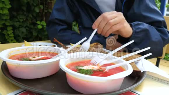 一位游客用塑料盘子在露天的夏季咖啡馆里吃饭视频的预览图
