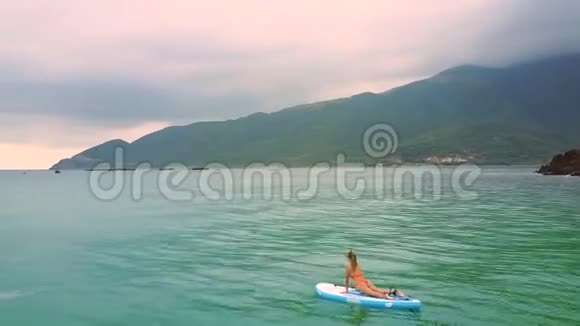 波浪把金发女人载在桨板上打开大海视频的预览图