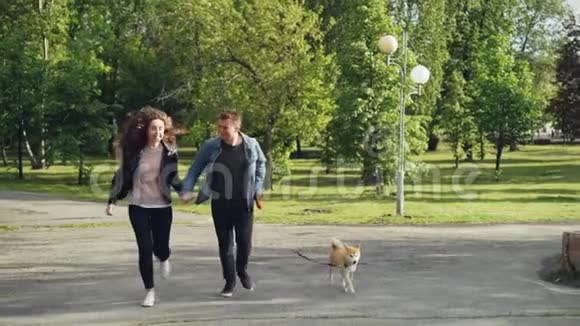 一对年轻的已婚夫妇在公园里跑步小狗享受自由与美丽的人一起活动视频的预览图