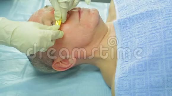一位女性美容师把胶原蛋白垫放在男人的下眼睑上视频的预览图