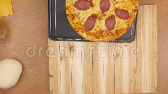 热气腾腾的意大利香肠披萨从平底锅转移到木桌上没有一个男人或女人在缓慢地移动视频的预览图