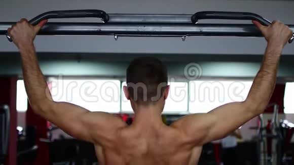 在健身房一个男人用肌肉发达的手臂做秋千视频的预览图