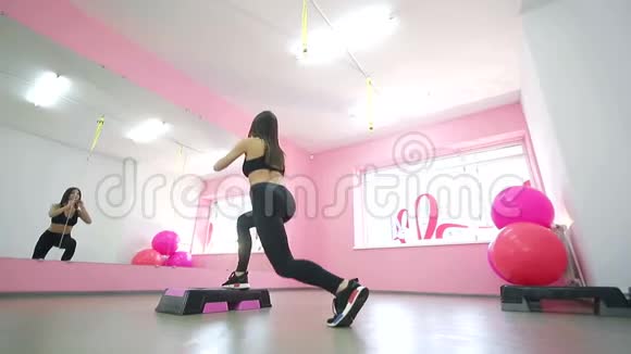 一个可爱的黑发女人在镜子前做健身运动在健身房里爬健康生活方式视频的预览图