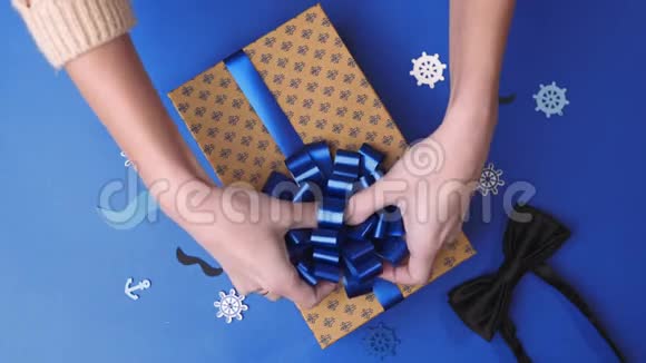 为男人把蝴蝶结粘到现在的盒子里包装现在包裹装饰带礼物的盒子4kUHD视频的预览图