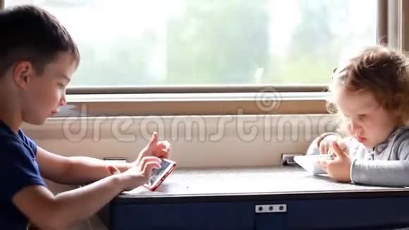 女孩和男孩在火车上玩智能手机的游戏视频的预览图