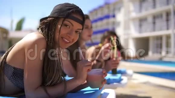 美丽的年轻女孩害怕和她的女性朋友一起喝鸡尾酒在游泳池旁放松夏日泳池派对视频的预览图