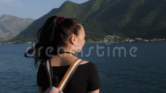 镜头围绕着一个欣赏大海和山脉的年轻女人视频的预览图