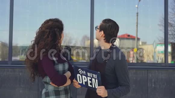 快乐迷人的侍者们拿着打开的石板看着新开的咖啡馆的窗户然后转向摄像机视频的预览图