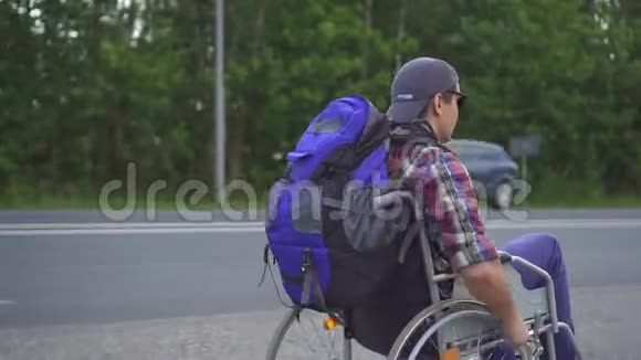 残疾人坐轮椅背着背包在高速公路上旅行后视图视频的预览图