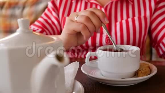 女人拿起小勺子开始在一杯热红茶里搅拌糖近距离操作射击视频的预览图