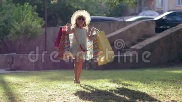 快乐的购物者女孩在草坪上逛完商店后买了许多新衣服作为衣柜和熊的包装视频的预览图