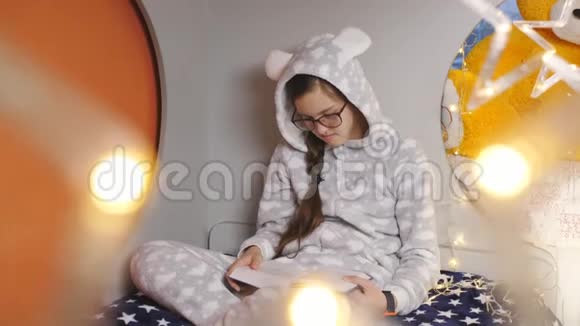 少年穿着暖和的睡衣坐在床上看书的女孩视频的预览图